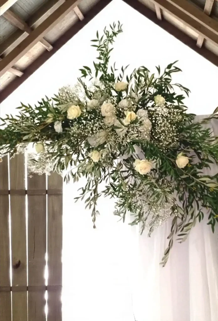 Arche de cérémonie laïque décorée de feuillage d’olivier et fleurs blanches en extérieur