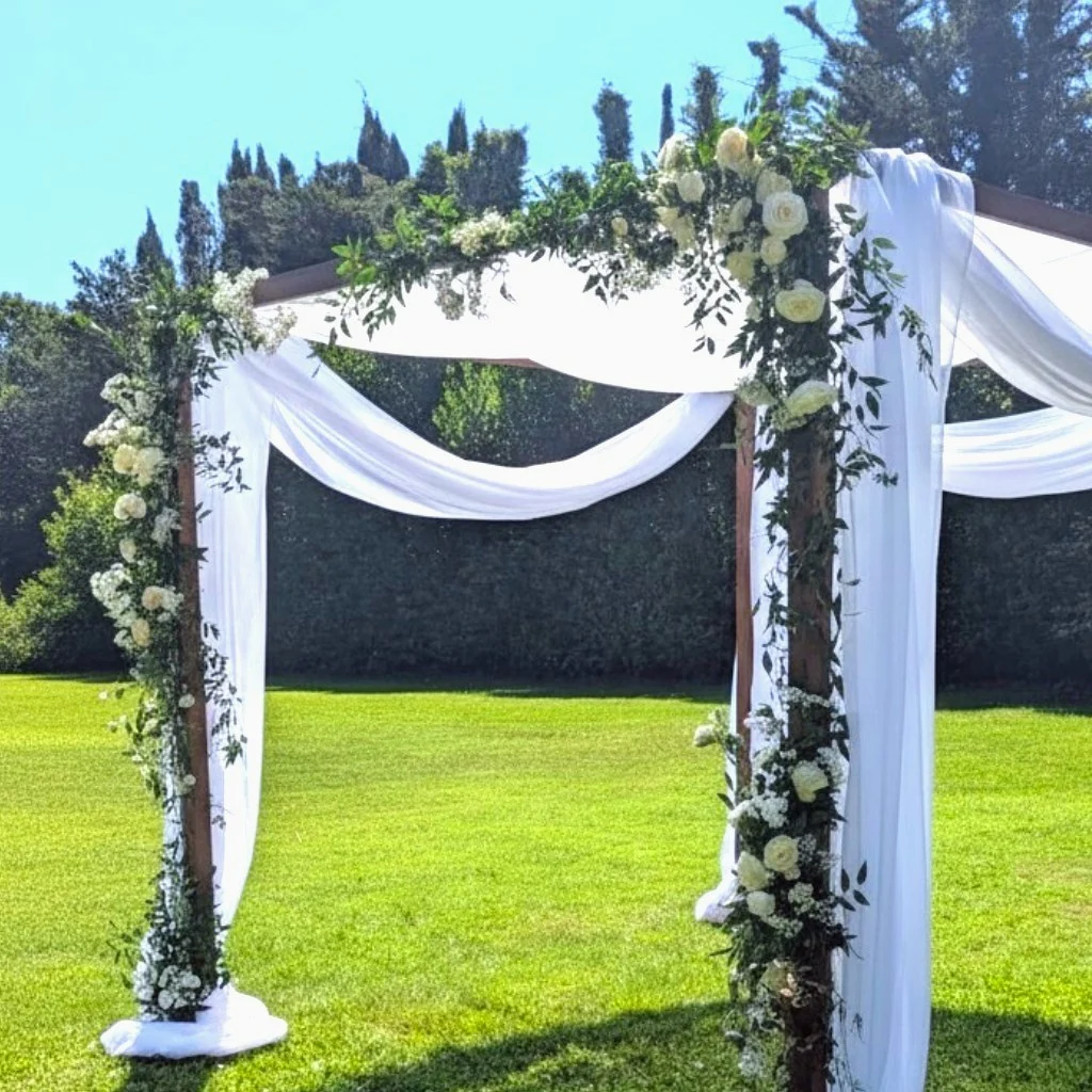 Wooden chuppah with white drapes and fresh flowers for a Jewish wedding - Iliade Création Carqueiranne Var